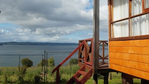 Une cabane en bois dotée d’une terrasse en bois et d’un escalier menant à une fenêtre donnant sur une étendue d’eau.