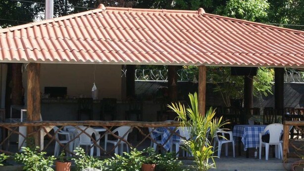 An outdoor patio with a tiled roof, surrounded by plastic chairs and tables, and potted plants. - Residencial Rio Hato (Rio Hato)