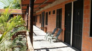 A building with a brick facade, large black doors, and a covered outdoor seating area with chairs. - Residencial Rio Hato (Rio Hato)
