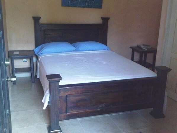A bedroom with a wooden bed, two nightstands, and a small table.
