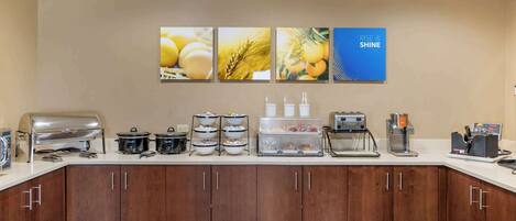 A kitchen area with a buffet setup, including a grill, pots, and a coffee machine.