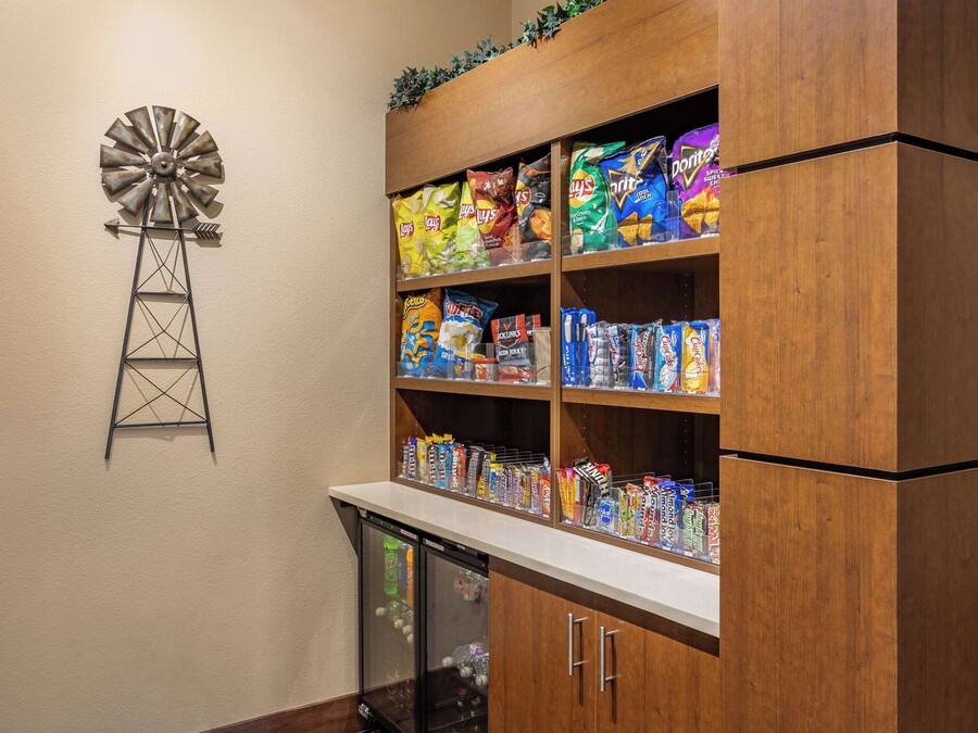 A snack shelf stocked with various chips and snacks, a small refrigerator, and a windmill decoration on the wall.