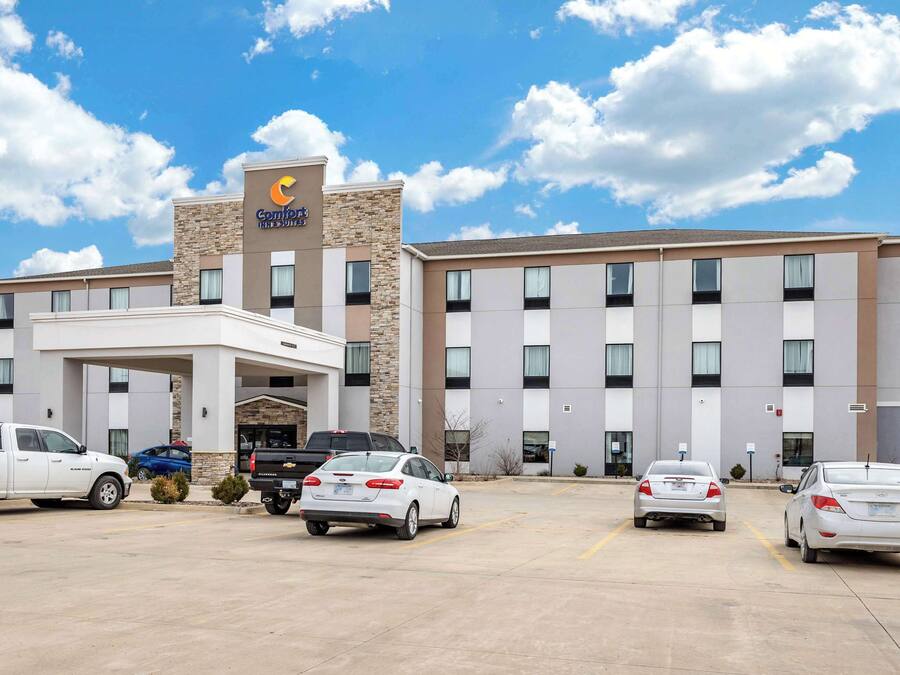 A hotel with a modern design, featuring a prominent entrance and multiple parking spaces.