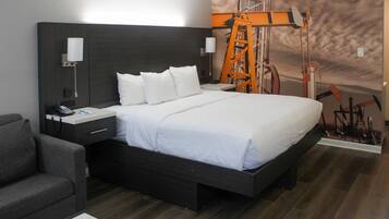 A modern hotel room with a large bed, a nightstand with a phone, a lamp, and a wall-mounted light.