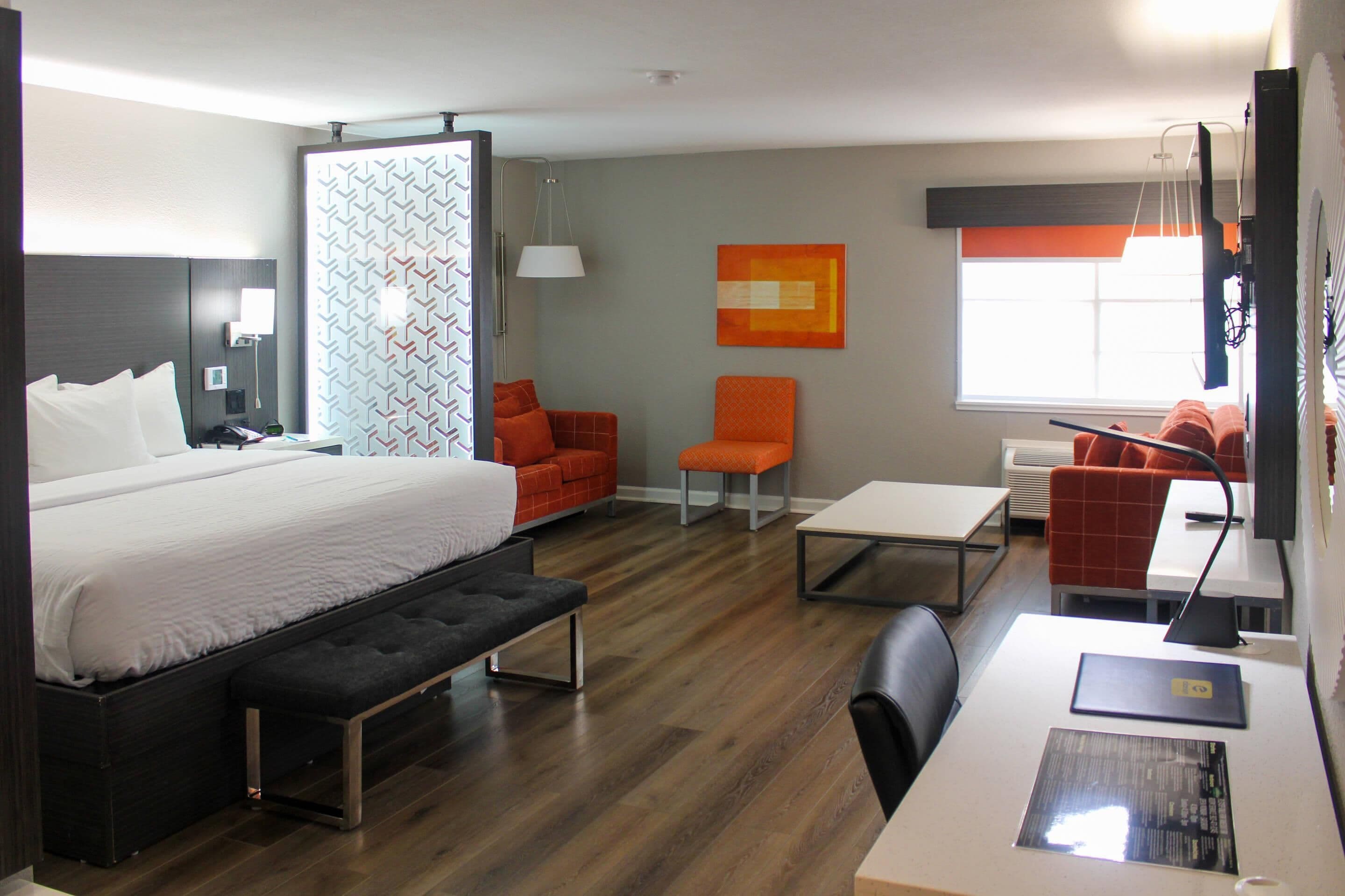 Una habitación de hotel moderna con una cama grande, un escritorio con computadora, una silla y un sofá.