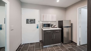 A compact kitchen with dark cabinets, a microwave, a refrigerator, and a white countertop. - Clarion Pointe Marshall (Marshall)