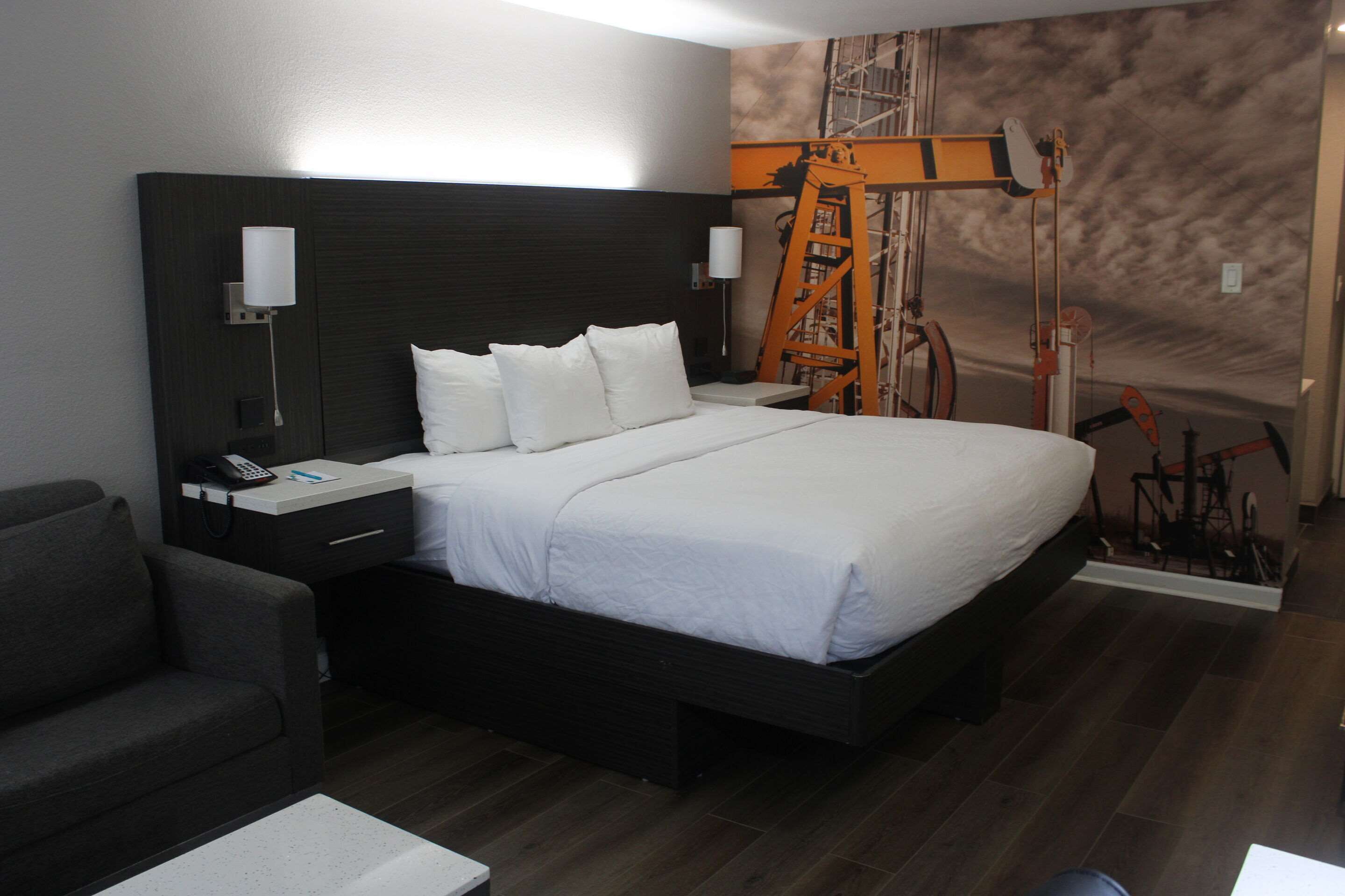 Une chambre d’hôtel moderne avec un grand lit, une table de chevet avec une lampe, un petit bureau et une chaise.