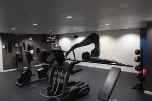 A gym with exercise equipment, a television, and a clock on the wall. - Clarion Pointe Marshall (Marshall)