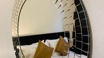 A round mirror with a mosaic border on a wall.