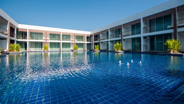 Un hôtel moderne doté d’une grande piscine intérieure, de nombreux balcons et offrant une vue sur un ciel d’un bleu éclatant.