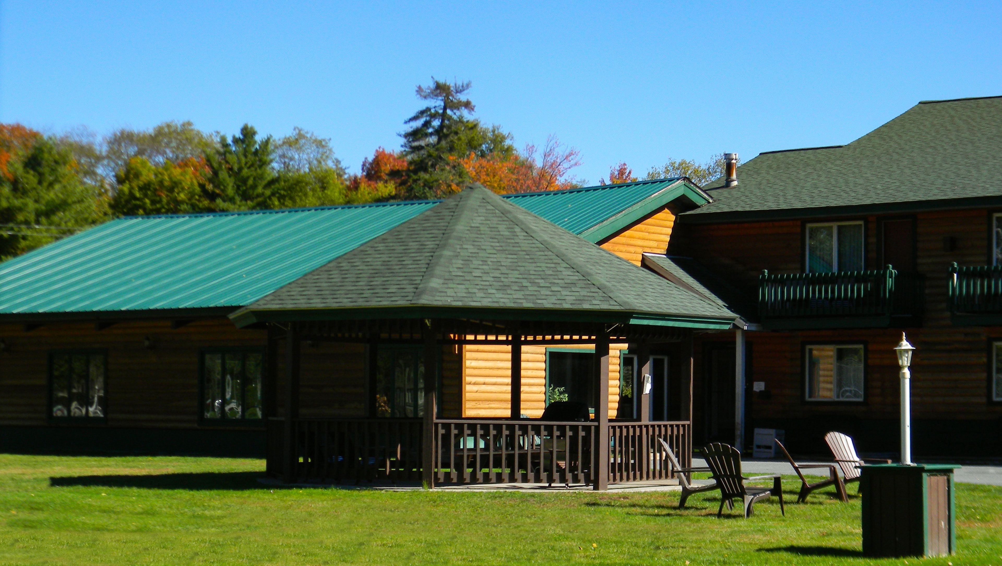 A lodge with a green-roofed main building and a separate wooden structure with a porch.