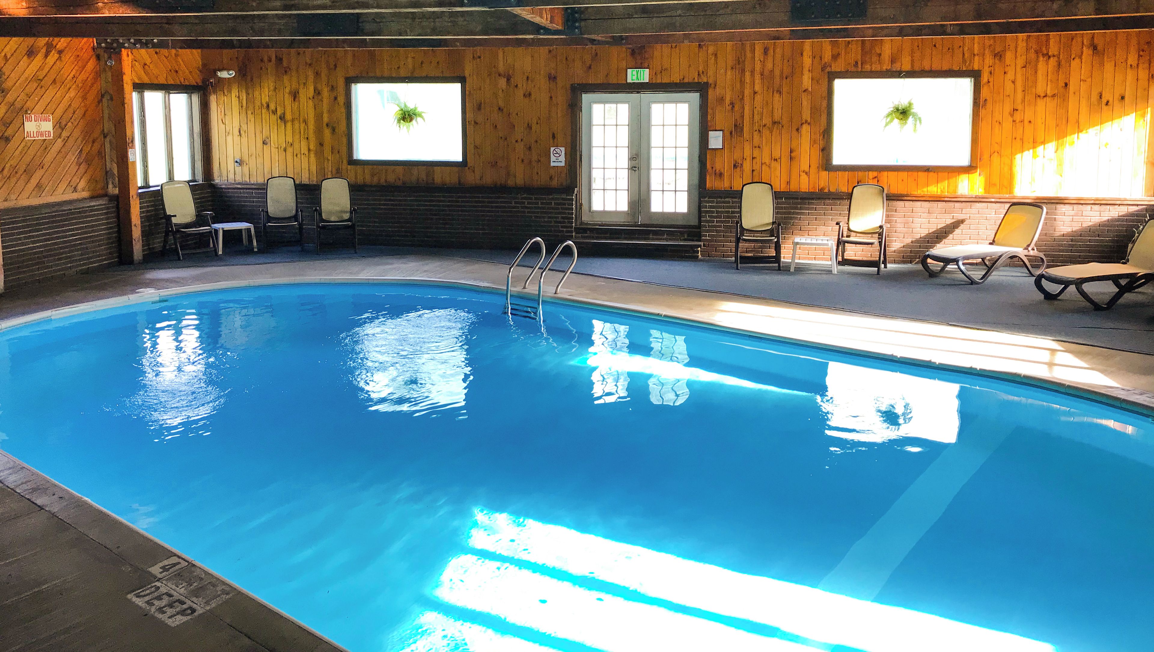 An indoor swimming pool with a wooden interior, a diving sign, and a bench area.