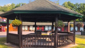 A gazebo with a green roof and a wooden railing, surrounded by a grassy area. - Adirondack Lodge Old Forge (Thendara)