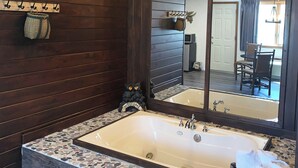 A bathroom with a large mirror, a bathtub, and a small decorative item on the wall. - Adirondack Lodge Old Forge (Thendara)