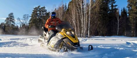 A snowmobile in a snowy landscape with trees in the background.