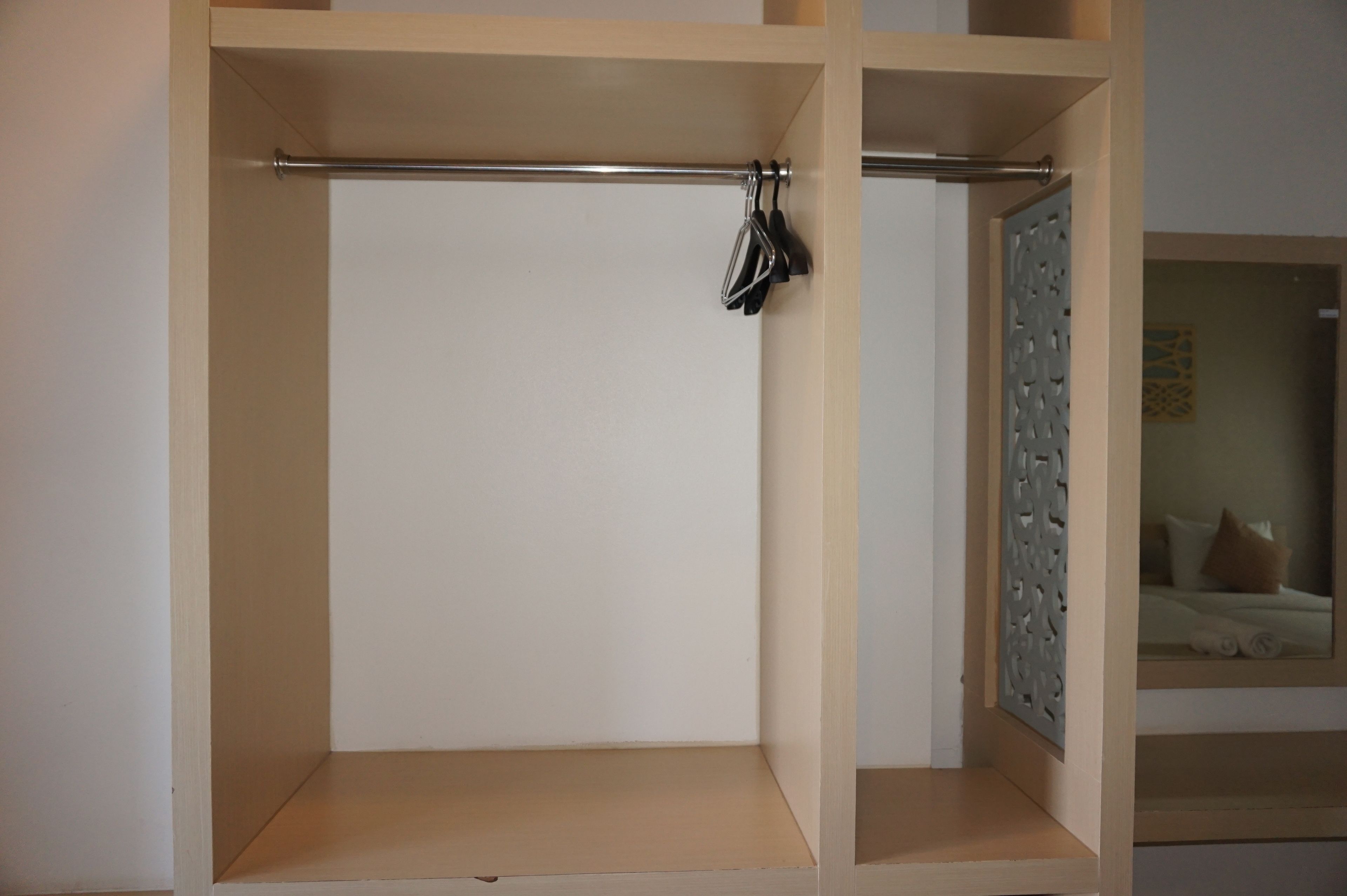 Una habitación minimalista con un armario de madera, una barra metálica y un panel decorativo.