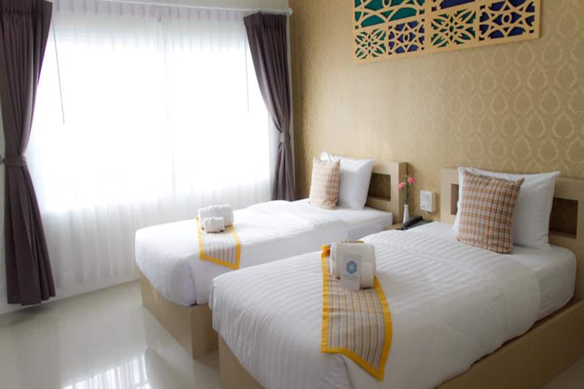 Habitación de hotel con dos camas, un ventanal con cortinas y un panel decorativo en la pared.