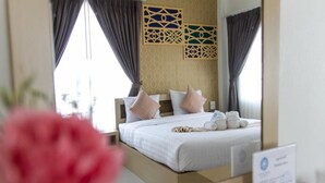 Een hotelkamer met een bed, gordijnen en een decoratief wandpaneel.
