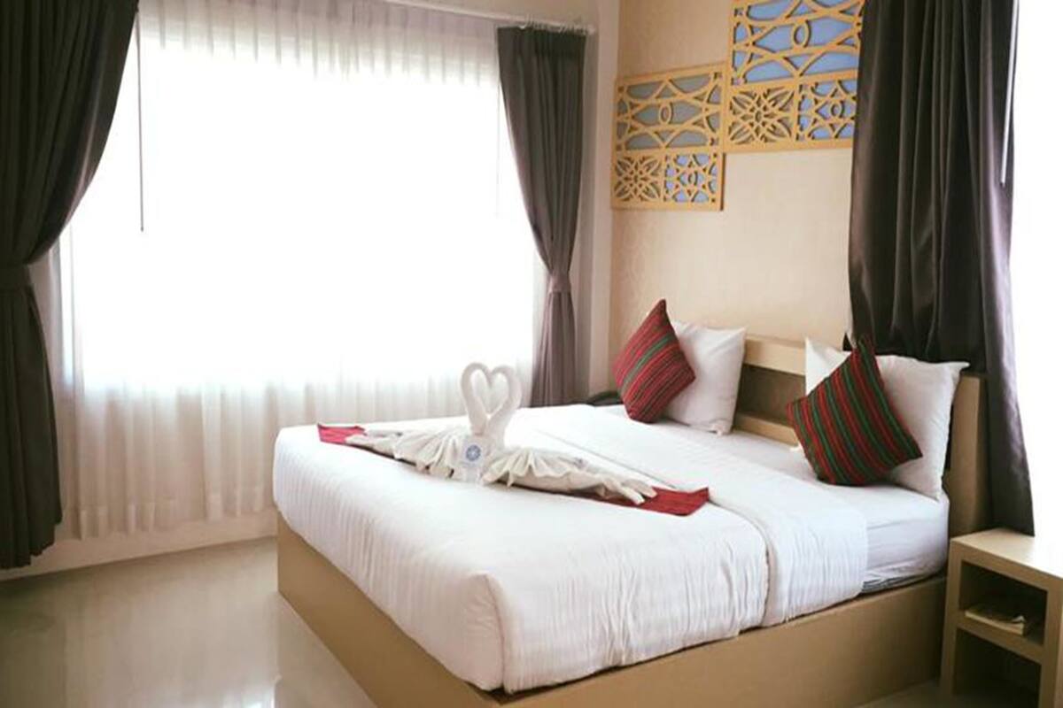 Habitación de hotel con una cama grande, dos almohadas, una mesita de noche y un panel decorativo en la pared.