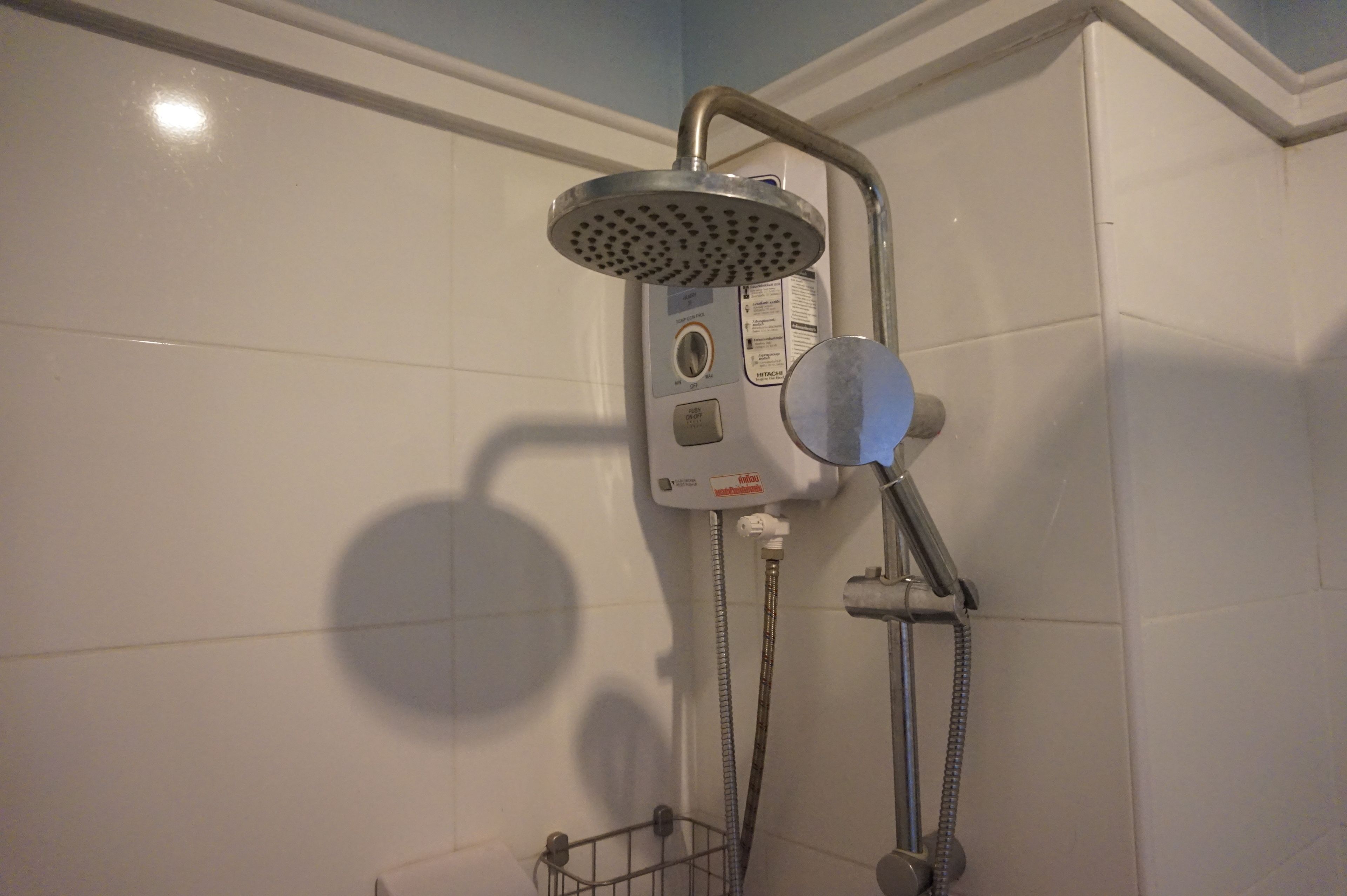A shower with a handheld showerhead, a control panel, and a hose.