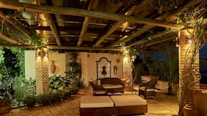 Une terrasse extérieure avec un sol en pierre, des meubles en bois et des plantes en pot.