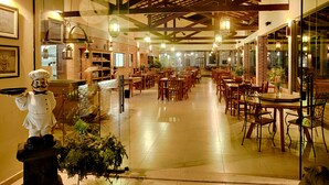Un restaurant spacieux avec de hauts plafonds et des poutres en bois, comprenant plusieurs espaces de restauration avec des tables et des chaises.