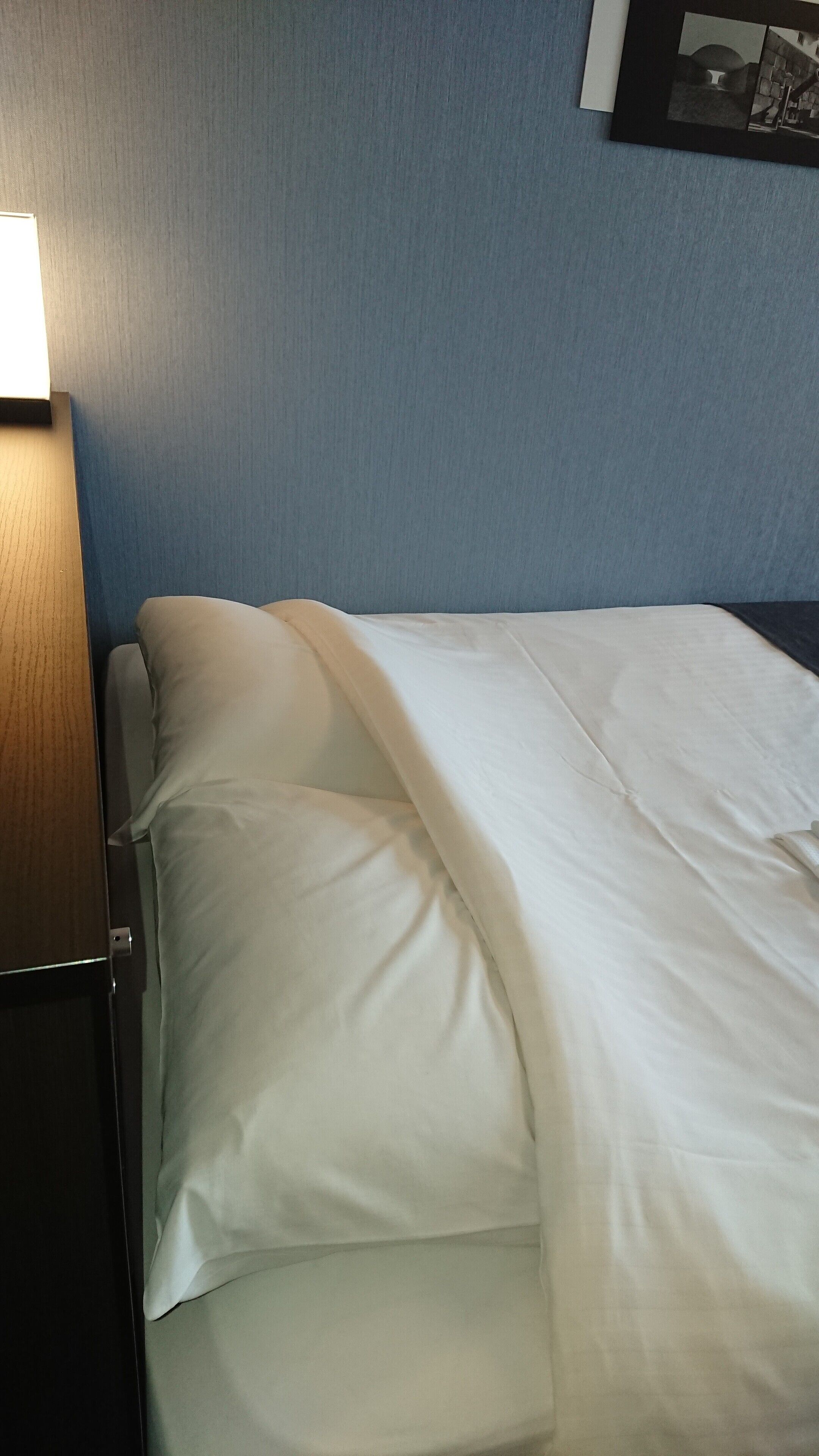 A bed with white bedding in a room with blue walls.