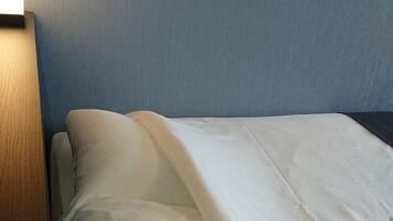 A bed with white bedding in a room with blue walls.