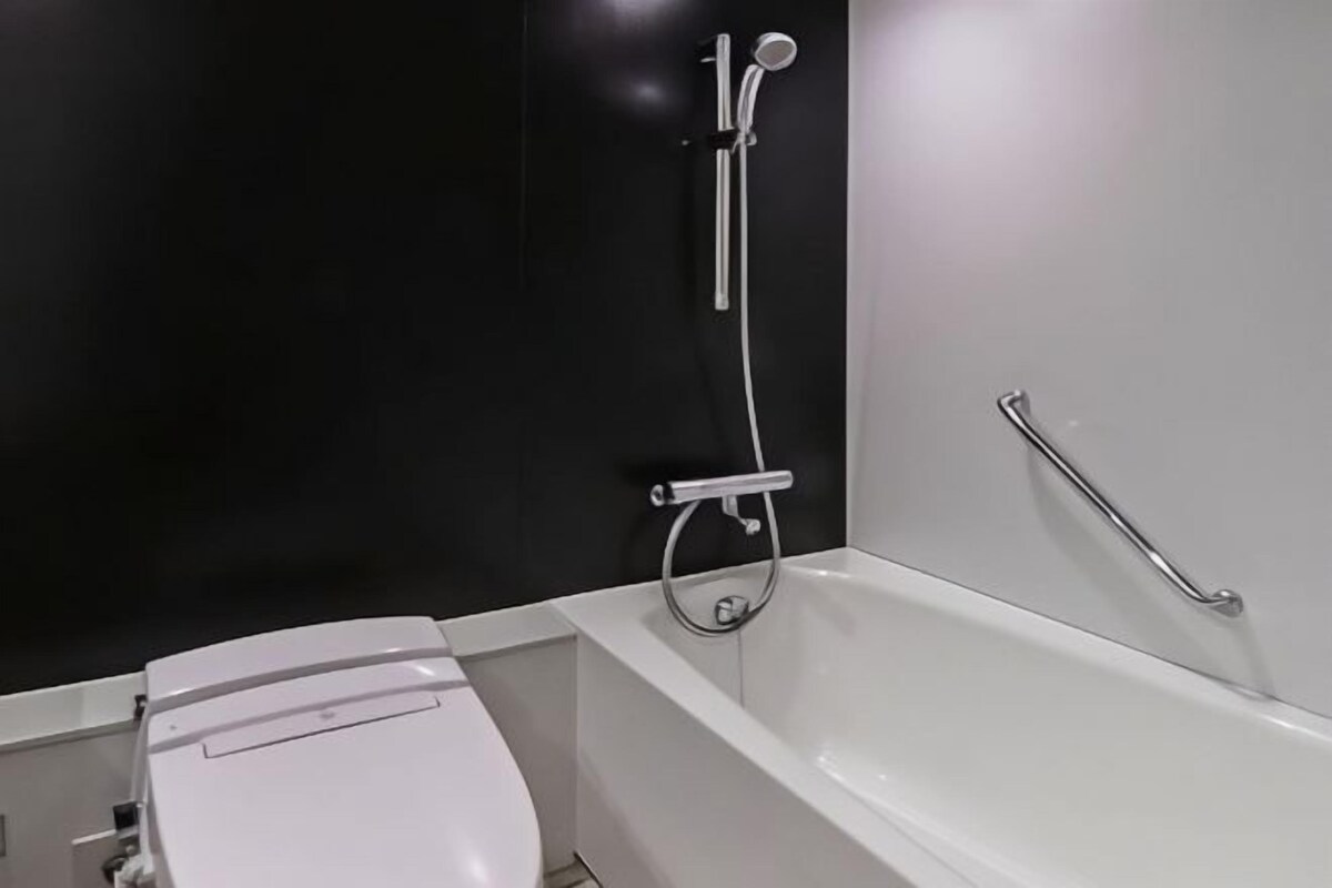 Un baño moderno con una bañera blanca, inodoro y cabina de ducha.