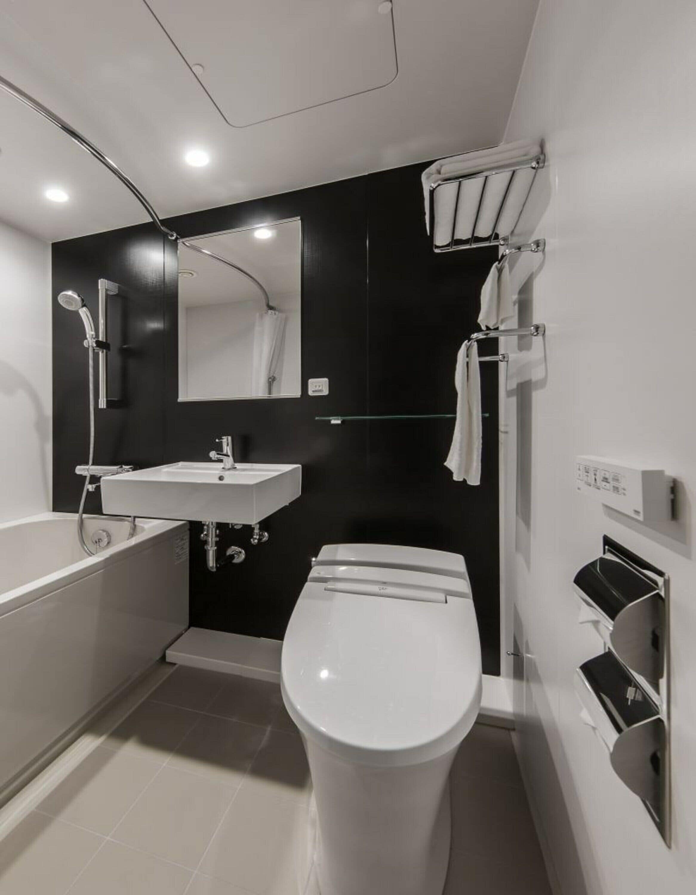 Un baño moderno con bañera, inodoro, lavabo y espejo.