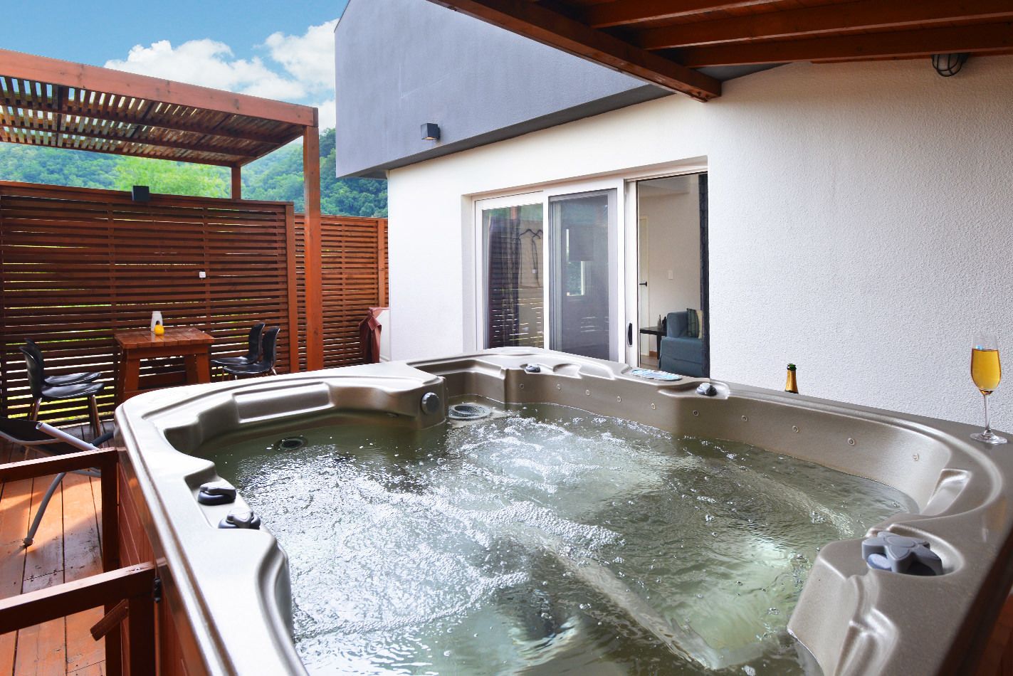 A hot tub with a wooden deck and a covered patio area.