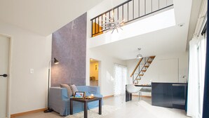 A spacious living area with a high ceiling, a staircase, and a modern kitchen. - Skylake Pension (Hongcheon)