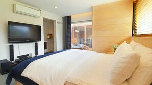 A modern hotel room with a large bed, a flat-screen TV mounted on the wall, and a view of the outside through a large window. - Skylake Pension (Hongcheon)