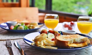 A meal with a sandwich, fries, and a salad, accompanied by two glasses of orange juice.