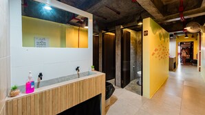 A modern bathroom with a wooden vanity, a mirror, and a yellow accent wall. - Sleeper Hostel (Krabi)