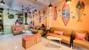 A hotel lobby with sofas, a reception desk, and wall art. - Sleeper Hostel (Krabi)