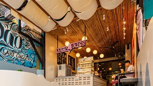 A staircase leading to a café with a neon sign, a mural, and a plant. - Sleeper Hostel (Krabi)