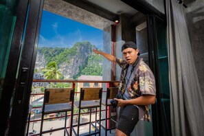 A man standing on a balcony with a view of a mountain and palm trees. - Sleeper Hostel (Krabi)