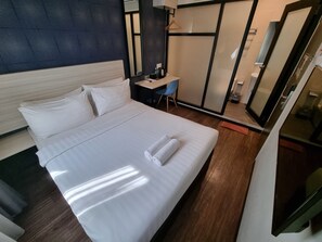 A hotel room with a large bed, a desk, a chair, and a mirror. - The Square Hotel (Johor Bahru)