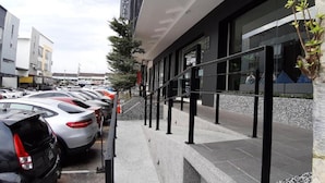 A modern hotel with a covered outdoor area, a parking lot with several cars, and a tree wrapped in protective material. - The Square Hotel (Johor Bahru)
