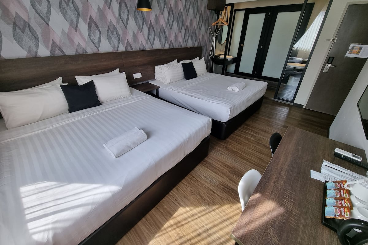 A hotel room with two beds, a wooden desk, and a mirror.