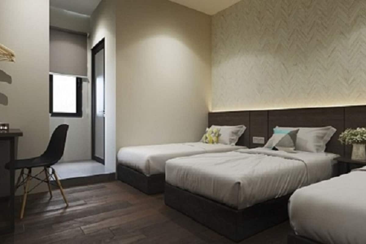A modern hotel room with two beds, a desk, and a chair.