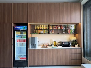 Une petite cuisine équipée d’un réfrigérateur rempli de boissons, d’une machine à café et d’un four à micro-ondes.