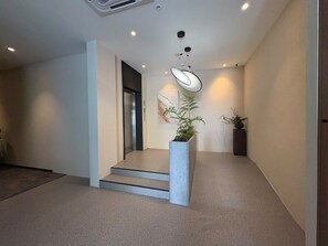 A modern interior with a staircase, a potted plant, and a ceiling light fixture. - The Square Hotel (Johor Bahru)