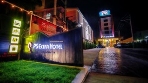 A hotel entrance with illuminated signage, a paved walkway, and a building with multiple floors. - PS Extra Hotel (Hat Yai)