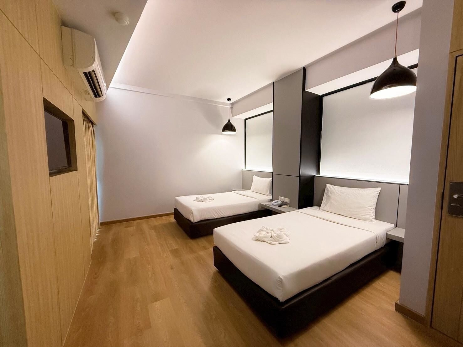 A modern hotel room with two beds, a large mirror, and a pendant light.