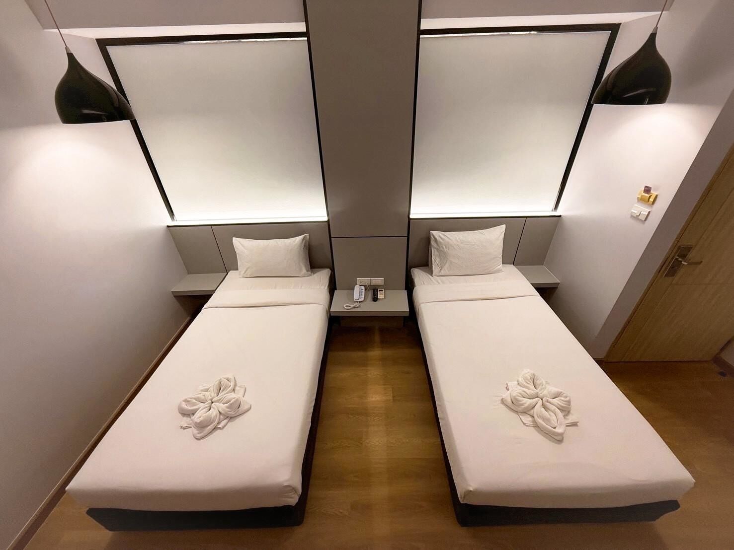 A mirrored room with two beds, each with a pillow and a towel.