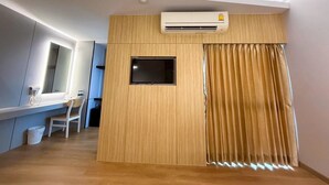 A modern hotel room with a wooden accent wall, a flat-screen TV, and a large window with curtains. - PS Extra Hotel (Hat Yai)