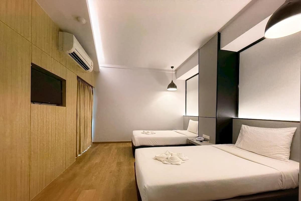 Quarto de hotel com duas camas, televisão de tela plana, ar condicionado e mesa de cabeceira com telefone.