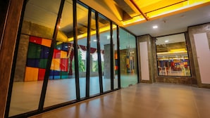A modern interior with glass partitions, a tiled floor, and a visible staircase leading to an upper level. - PS Extra Hotel (Hat Yai)